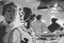 Placeholder: black and white storyboard, wide, on the Foreground there is a man and a girl in profile close to the camera, we see just their upper body and chins as they are passing by, and in the background, 3 chefs, scattered throughout the kitchen cooking, frying, cutting