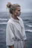 Placeholder: Standing in the grey-north sea with white clothes. Girl with a bun. Rains heavily. You see her face, blues eyes and blond hair.