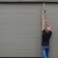 Placeholder: skinny guy lifting garage door on a rainy day