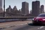 Placeholder: A Tesla 'Model 3' is going at a high speed, on the 'FDR Drive', eastern Manhattan. (CINEMATIC, WIDE ANGLE LENS, PHOTO REAL)