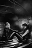 Placeholder: Margot Robbie and Georgia Henshaw tied up back-to-back in black leather, trapped in a flooding chamber.