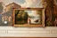 Placeholder: a classic painting on a musiume wall showing a lady standing next a river in coutry side with a luxury frame