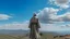 Placeholder: A Morisco general in an Arab dress stands with his back on the top of a mountain, in front of him is a flat land, and the sky is blue and full of clouds.