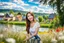 Placeholder: Young woman in flower field in country side ,river, houses,blue sky ,nice clouds,god rays