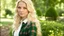 Placeholder: Photo is in sharp focus with high resolution and is a closeup of a beautiful and slender caucasian 17 year old teen girl with long wavy platinum blonde hair. She is wearing a white blouse and green plaid jumper. She is in a garden gazing at the viewer.