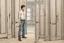 Placeholder: man in jeans and a shirt standing in a room of doors