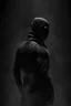 Placeholder: Background is dark grey, almost black. There is a head and torso silhouette looming in the picture, completely masked by a black kevlar suit.