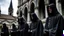 Placeholder: hooded monks in black robes in front of cathedral