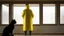 Placeholder: A person wearing a yellow raincoat is standing in a deserted room looking out a window. A black cat is sitting nearby, watching the person.