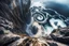 Placeholder: at the base of the rocky mountain peninsula, a great whirlpool waterfalls into deeper unknown depths