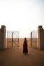 Placeholder: a woman standing in front of a gate like a mirror in the middle of the desert in foggy sky