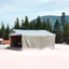 Placeholder: A super high definition photo of an open space studio with structures. A transparent tarpaulin covers a ruined building. There is a group of fir trees in the background and a high hill in the distance. The surface below is in a pastel color. Fog is present.
