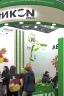 Placeholder: Corner green exhibition stand of a food company with product displays and a meeting area