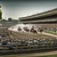 Placeholder: Top photo of horse racing on a stadium track with a large crowd