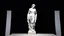 Placeholder: A white marble statue of a draped figure against a black velvet backdrop, illuminated by a single, dramatic spotlight.