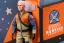 Placeholder: Mike pence G.i. Joe toy doll Space force uniform With accesories inside a blister packaging hanging on a Wallrack in toystore, fluorescent orange, toy guns, wide angle shot whole body, black moonboots, fullsize, green