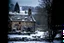 Placeholder: Vintage image of Snow falling heavily in the Cotswald area of England. A stone cottage with smoke coming out of the chimney. Surrounded by stone fences. In the background a startled group of deer look this way. A thick forest behind them.