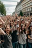 Placeholder: on a wide boulevard of a city, a huge crowd of people of all ages, smiling and joyful with their hands in the air.