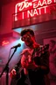 Placeholder: An spanish Guy with "popsicle" big eyes "Enrique" performing at dance club, his name is "Enrique" Red roses On stage, red Neon lights and smog, and "Din KEBAB I NATT" big sign on the wall, serenade under balcony,a female lamb on the balcony
