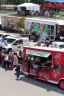 Placeholder: awesome looking food truck with many people lined up . Show the food truck fleet in the background.