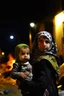 Placeholder: Palestinian girl wears Palestinian keffiyeh Carrying a small child , Destroyed Buildings , with a Explosions, at night