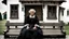 Placeholder: gloomy-looking old angry women sitting in black hungarian villager dress and wearing east european black head scharf on wooden bench in front of white old house outside in an authentic east european ,hungarian village, high detalied, professional photo, high qualit, high textures. The high-resolution image captures the essence of authenticity and realism, transporting the viewer to another time and place.