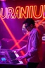 Placeholder: French cool synth player, he is called "Jean-Maurice Brûlée" performing at dance club, his name is "Jean-Maurice Brûlée" , white and orange Neon lights and oraNGE smog, and "URANIUM" big sign on the wall, he is playing on synthesizers on stage with lot of laser beams and wearing black sunglasses, an earth is projected in background