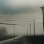 Placeholder: An empty road on a misty day. Telegraph poles and wires. Muted tones. Tilted high horizon. With blotches, blurry areas and lens noise and grain. Photo 4k