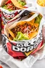 Placeholder: "Taco in a Bag" which consists of an open Doritos chip bag with sides rolled down, containing Doritos chips and cooked ground beef and lettuce and shredded cheese and chopped tomato pepper and onions and topped with more nacho chips, food blogger photography