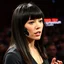 Placeholder: English female with straight dark hair and bangs with a Vestigial synthetic mechanical full face implant with ersatz multi-modal gadget facial appendages giving a speech, absurd psychology, metaphoric situational photograph, background is a TED talk symposium with crowd,
