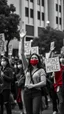 Placeholder: People going on strike with hand’s fest up and wearing masks all picture is in black and white style except a one beautiful girl in red is standing watching the crowd