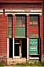 Placeholder: side of an old brick building, with windows, a doorway at the bottom, and worn out painted sign across the top