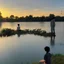 Placeholder: In the anime, a young male character is near the green lake in the sunset afternoon.