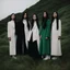 Placeholder: a group of women standing on top of a lush green hillside, inspired by Ren Hang, design milk, long black hair, whites, wanderers traveling from afar, trending on artisation, cloning spell, coat pleats, in twin peaks, submarine, by Helen Thomas Dranga, symetry, round-cropped, noire photo