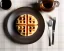 Placeholder: Round waffle butter with maple syrup plate, plaid napkin fork