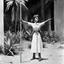 Placeholder: (1960’s stop-motion animation style of las reinas del combate en el suelo in Mexico) She is tied to a stake, her hands above her head, in the governor's villa
