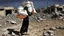 Placeholder: A Palestinian woman wearing a dress carrying very large bags of flour on her back, bending her back down in the destroyed Gaza City, and aid boxes descending from planes near the sea, with a large number of children looking up.