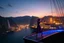 Placeholder: A modern city at the foot of the mountain. The entrance valley with a waterfall from a high rock.and huge sea with a very big ship in it, A beautiful lady dancer showing her performance in a poen stage on deck of ship in a top and midi skirt. at night ,dynamic color turnning lights