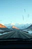Placeholder: surreal mountain road seen through a dirty truck front window, dirty golden snow and wind