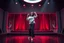 Placeholder: modern stage with gray-dark red theme artistic decoration , color full dynamic lighting, a beautiful lady in pants and blouse with shining silver jewels dancing, 3D recursive fractal structure animating background