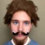 Placeholder: a guy with a toothbrush mustache and a hairstyle that consisted of combed-over hair with a part on the right side. He is of average height and has blue eyes and blond hair.