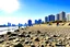 Placeholder: Sunny day, people, rocks, sand, distant modern city