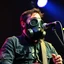 Placeholder: en skäggig motorcykelklubbs kille som försöker sjunga med en gasmask på en scen, gasmasker, dom kallar honom för babyface för att ser så barnslig ut