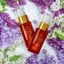 Placeholder: a small vial lies on a beautiful floral background top view, in the background there are beautiful spring flowers and a drop of cream, high-quality picture, top view