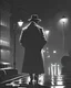 Placeholder: A dramatic, film noir-inspired illustration of a shadowy, rain-soaked city street at night, with a mysterious figure in a trench coat and fedora standing under a streetlight, evoking a sense of tension and suspense reminiscent of classic crime dramas.