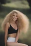 Placeholder: extremely tiny, thin, beautiful 21-year-old Sheena Greane with long, wavy curly blonde hair, wearing black strapless sports bra and cotton shorts, smiling a happy smile, extremely giant, oversized, humongous orbs, pitch black background, professional quality studio 35mm 8x10 uhd photograph,