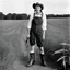 Placeholder: [photo by Helmut Newton] Grown up Pippi Longstocking: with a revealing overalls and cowboy boots in a field