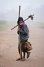 Placeholder: A homeless man carries a stick with his belongings on it.