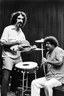 Placeholder: Frank zappa playing bongos next to a very fat black man