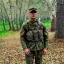 Placeholder: Soldier wearing tiger stripe camouflage standing in front of trees